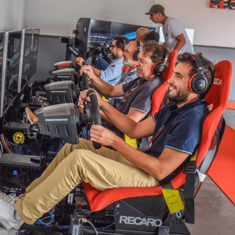 Collaborateurs d'entreprise en plein challenge de relais automobile sur des simulateurs de course.